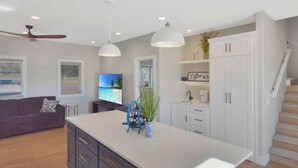 Una cocina moderna con una isla grande, armarios blancos e iluminación colgante.