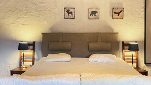 A neatly made bed with a grey headboard, two bedside lamps, and three framed animal silhouettes on the wall. - 4 Person Holiday Home in Hoor (Hoor)