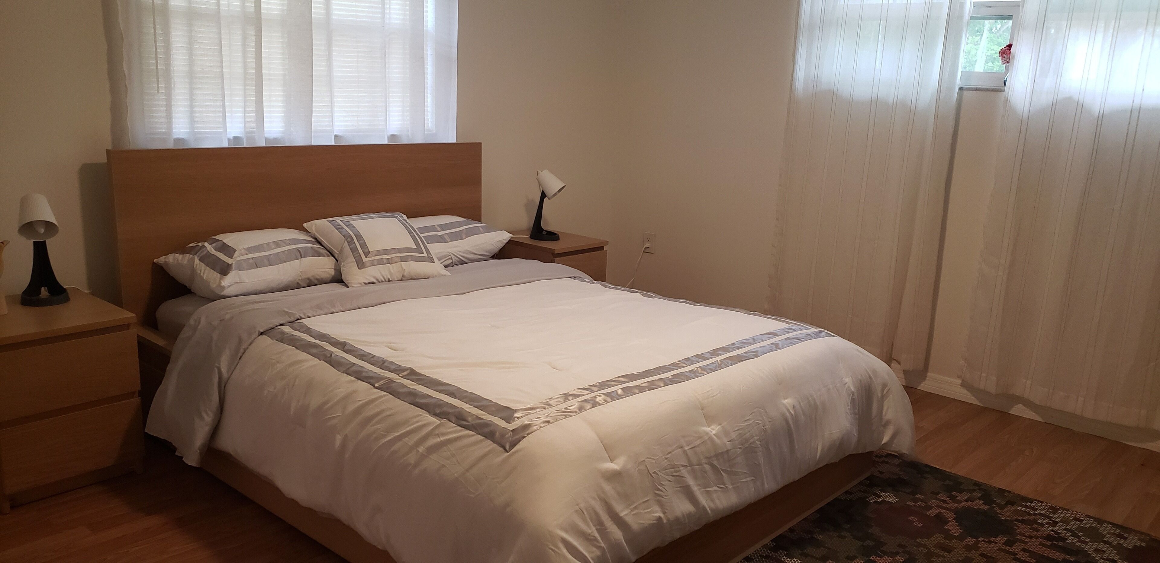 A neatly made bed with a wooden headboard, a bedside lamp, and a nightstand.