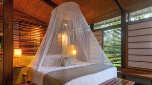 A bed with a canopy, wooden walls, and a window with blinds. - Jungle Villa with ocean view, shared infinity pool, wildlife, open-air living. (San Juan del Sur)