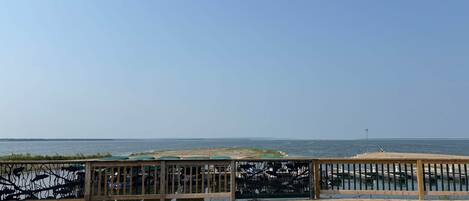 A wooden deck with a railing overlooking a calm body of water.