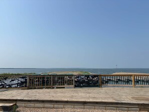 Une terrasse en bois dotée d’une rambarde, qui offre une vue sur une étendue d’eau calme.