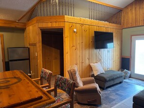 Een houten interieur met een eettafel, stoelen, een bank en een televisie.