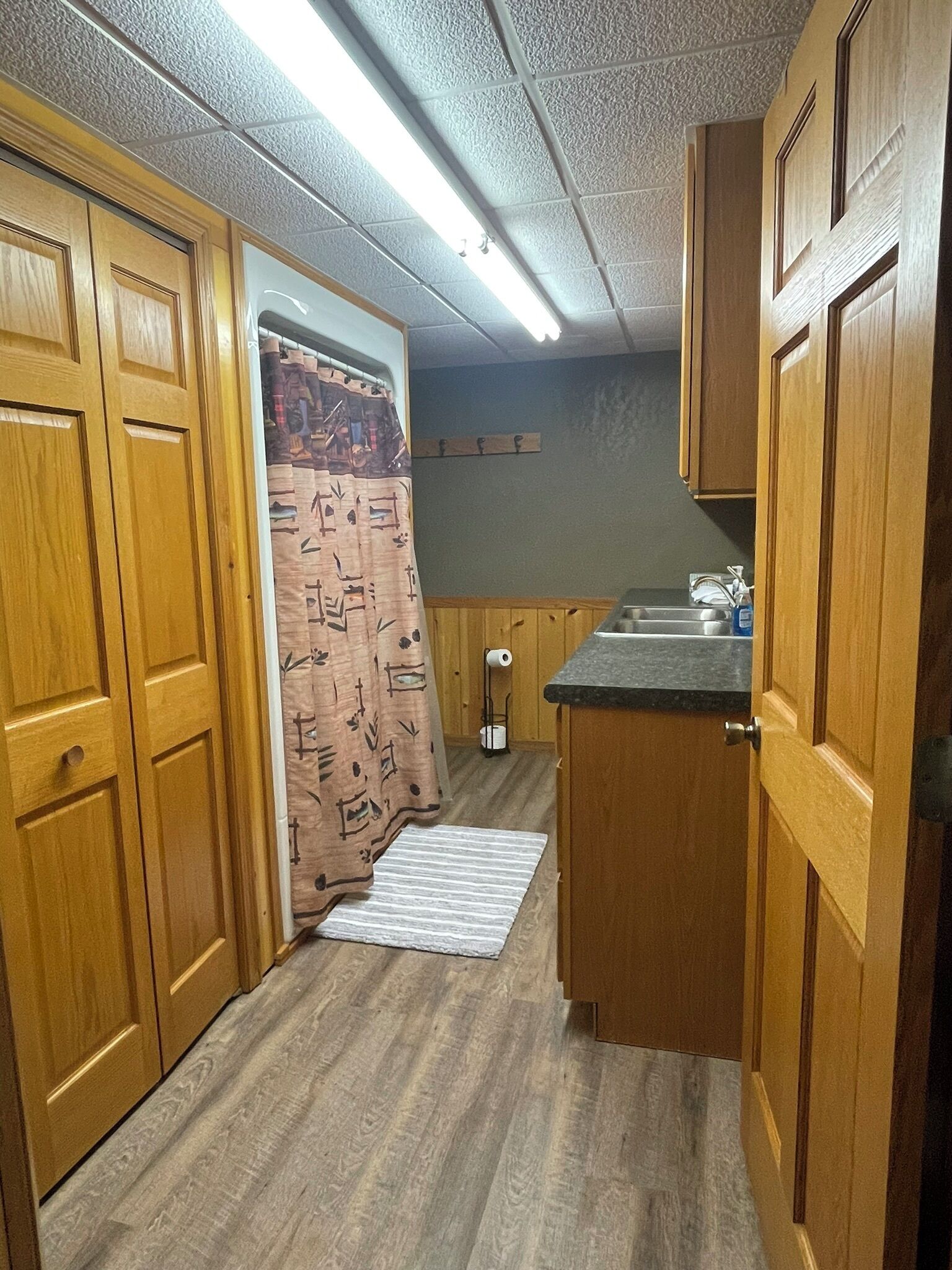 A compact kitchen with wooden cabinets, a countertop, and a shower curtain.