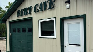 Un bâtiment portant l’inscription « BERT CAVE », avec une porte de garage verte et une porte blanche.