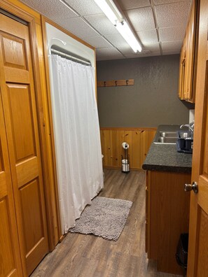 Een kleine keuken met houten kastjes, een roestvrijstalen spoelbak en een klein aanrecht.