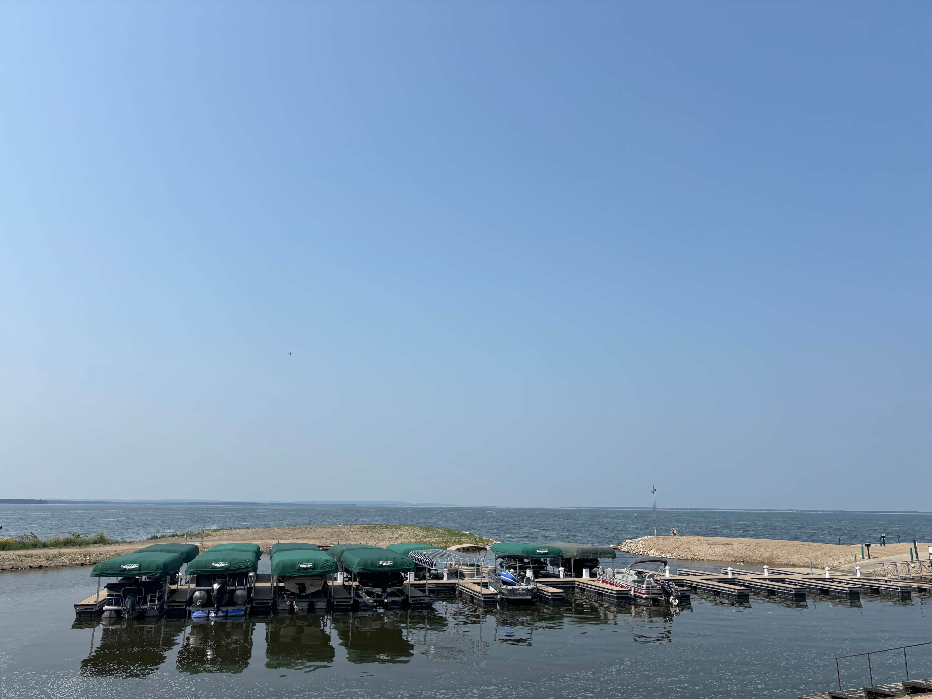 A marina with boats docked and covered by green canopies.