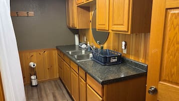 Una cocina con armarios de madera, encimera de granito, un lavabo y un escurreplatos.