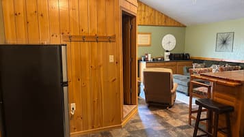 Una cocina con armarios de madera, un refrigerador, un reloj y un microondas.