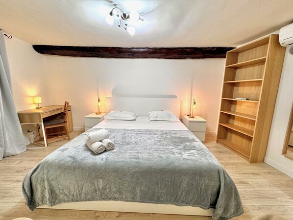 A bedroom with a bed, bedside tables, a desk, and a wardrobe.