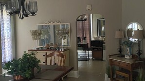 Un comedor con una mesa de madera y bancos, una araña y un espejo sobre la mesa.
