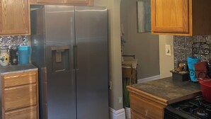 Una cocina con armarios de madera, un refrigerador de acero inoxidable, una estufa a gas y una lámpara de araña con varias luces.