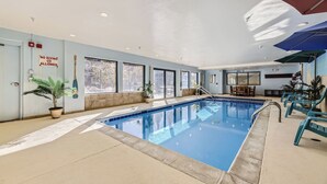 An indoor swimming pool with clear windows, a no diving allowed sign, and lounge chairs.