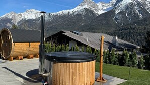 A hot tub in a landscaped area with a mountain backdrop. - Bergbijou - Luxurious vacation home with sauna, whirlpool, infrared and mountain views (Scuol)