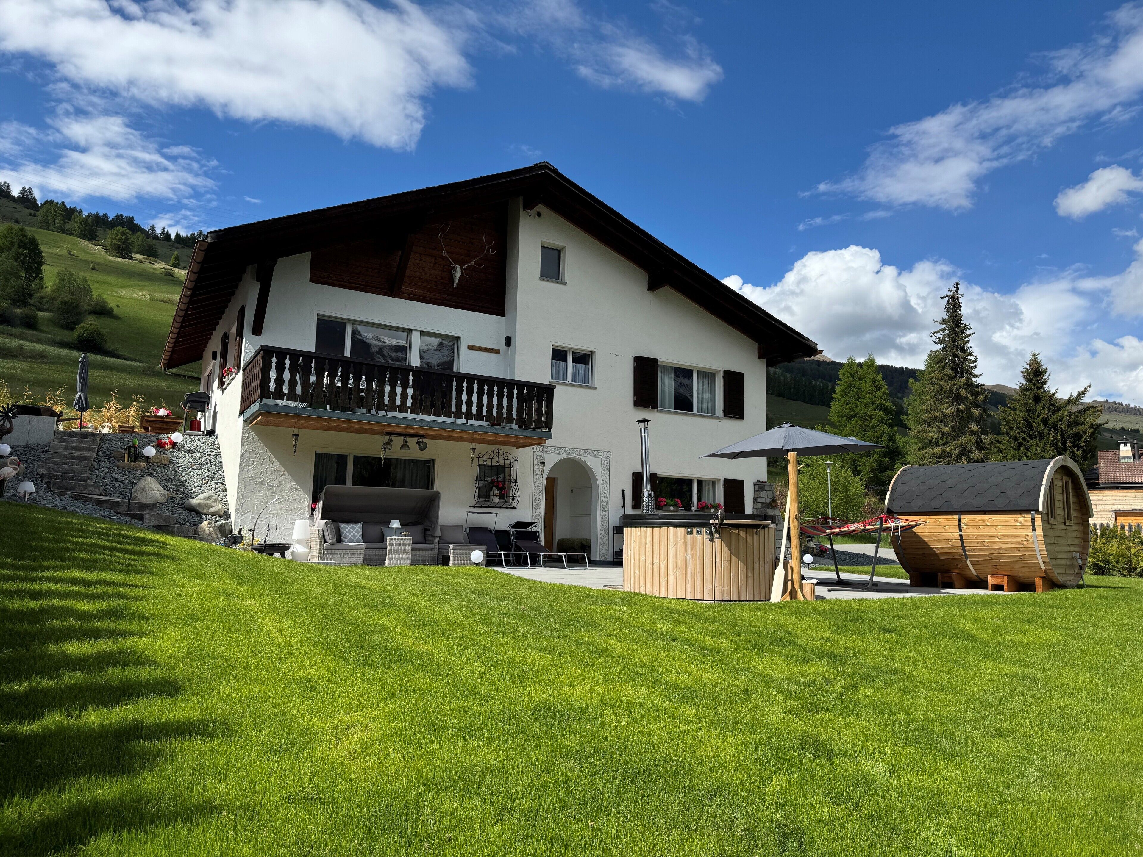 Une maison à deux étages avec un balcon, un espace barbecue et un tonneau en bois.
