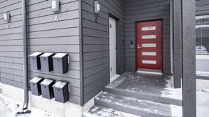 A building entrance with a red door, grey siding, and mailboxes. - Serviced Apts Rovaniemi Willamonkuja (Rovaniemi)