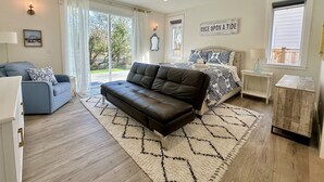 A spacious bedroom with a large bed, a leather sofa, a blue armchair, and a small wooden table. - True Luxury Waterfront: Dock, Kayaks & Hot Tub (Ocean Shores)
