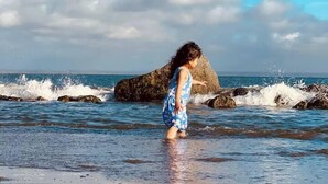 A beach scene with a person in a blue dress standing in shallow water near rocks. - True Luxury Waterfront: Dock, Kayaks & Hot Tub (Ocean Shores)