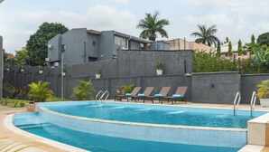 Una piscina con sillas de descanso y plantas en macetas.