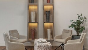 Un moderno salón con dos sillones, una mesa de centro y una estantería con adornos.