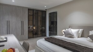 Un dormitorio moderno con una cama grande, un escritorio con una taza y frutas, y un armario con puertas correderas.