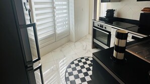 Una cocina moderna con encimera negra, tapete de suelo a cuadros y una ventana con persianas.