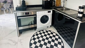 Cocina compacta con lavadora, horno, microondas y un tapete de piso a cuadros.