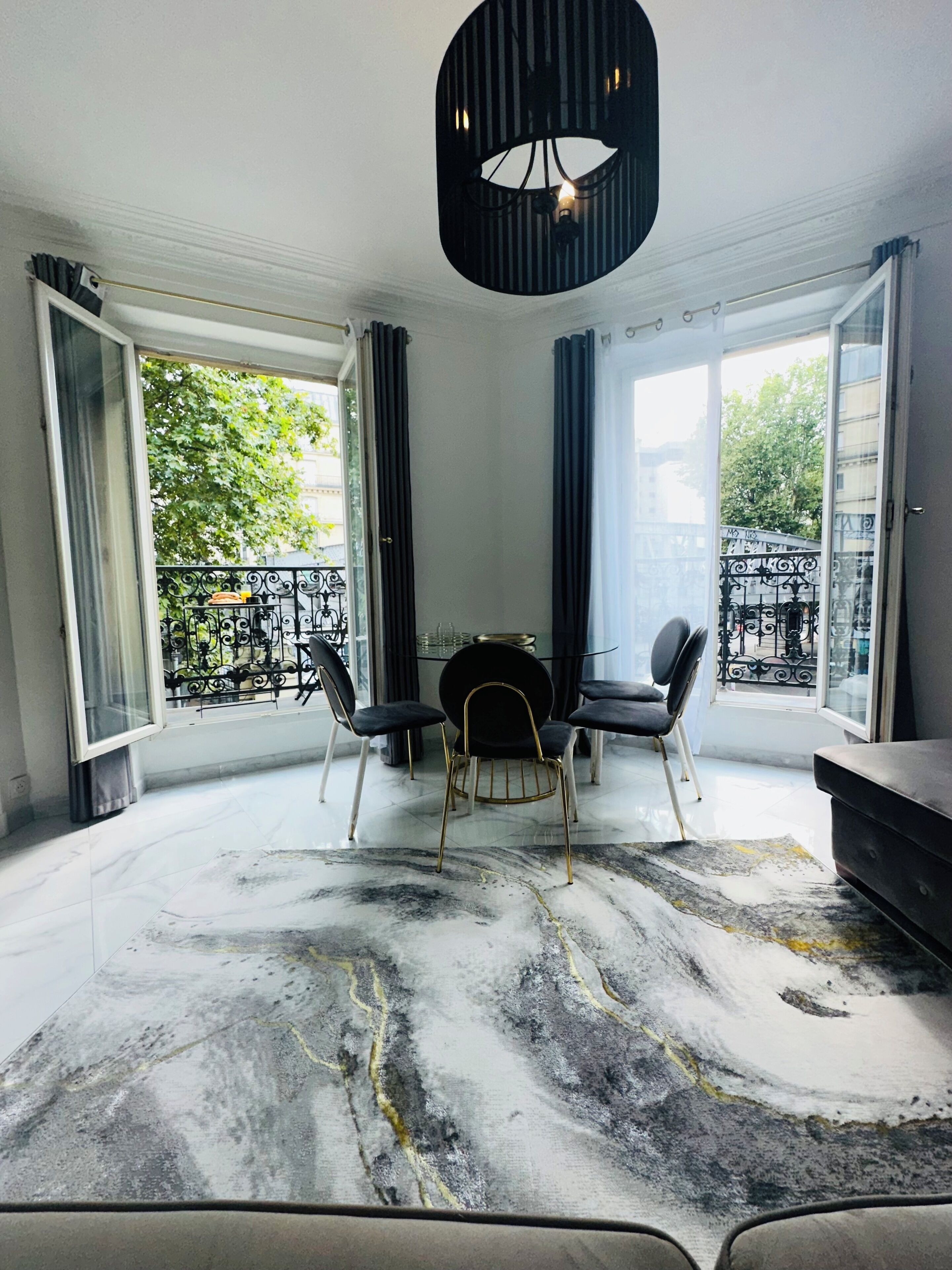 Un espace repas moderne avec un sol en marbre, une table ronde et des chaises noires.