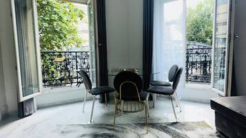 Een moderne eetruimte met een marmeren vloer, een ronde tafel en zwarte stoelen.