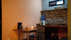 Une cuisine compacte équipée d’un réfrigérateur, d’une machine à café et d’un distributeur d’eau sur le plan de travail.