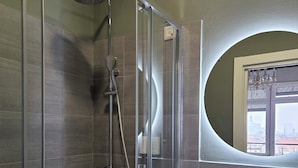 A modern bathroom with a glass-enclosed shower, a white sink, and a round mirror with a window view. - Corso Italia Rooms (Milan)