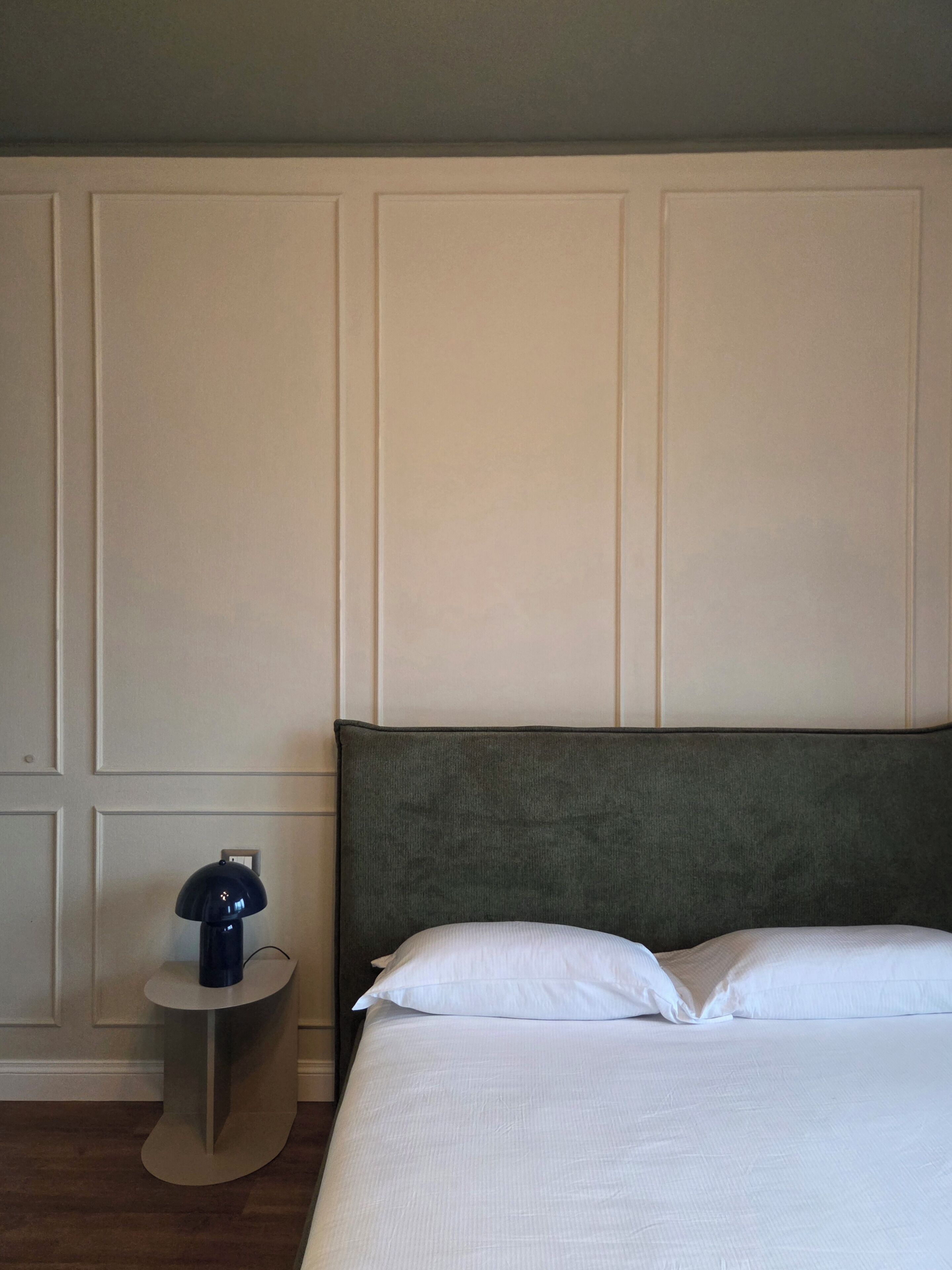 Una habitación de hotel con una cama, una mesita de noche y una lámpara.