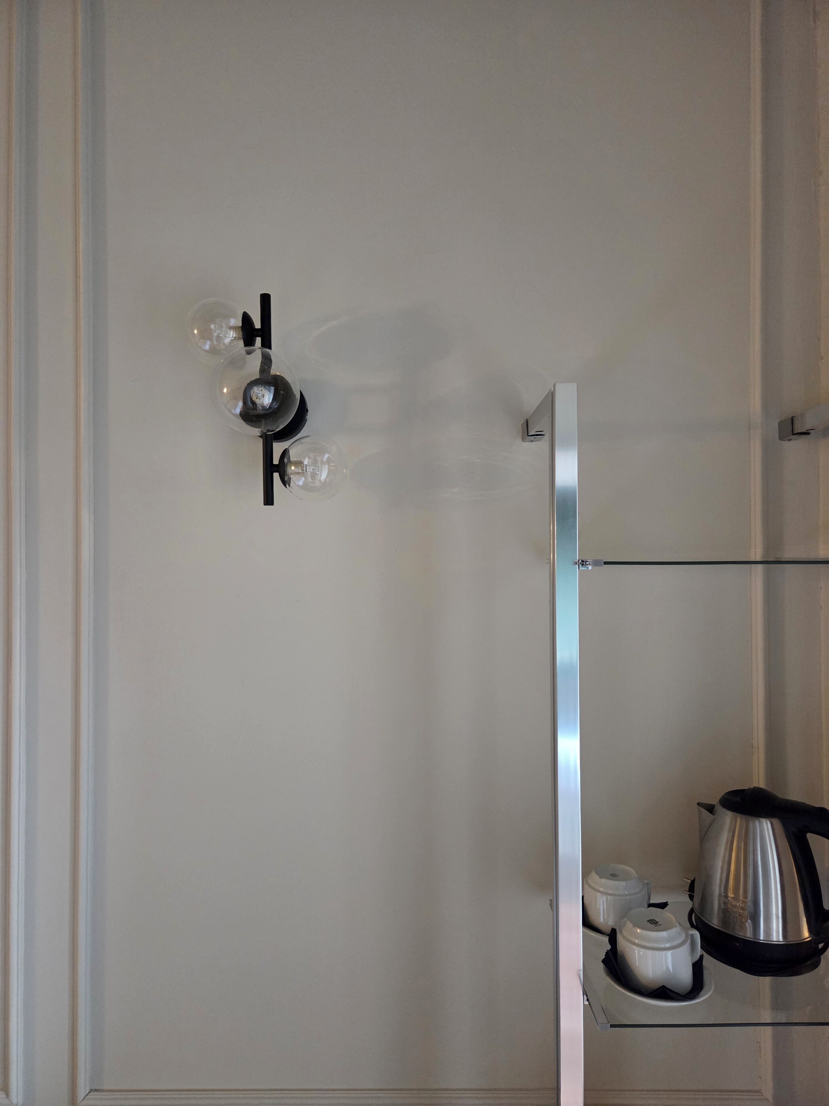 A bathroom with a shower, a towel rack, and a coffee maker on a shelf.