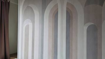 Une chambre à coucher avec un lit, un luminaire suspendu et un mur orné d’un motif à rayures.