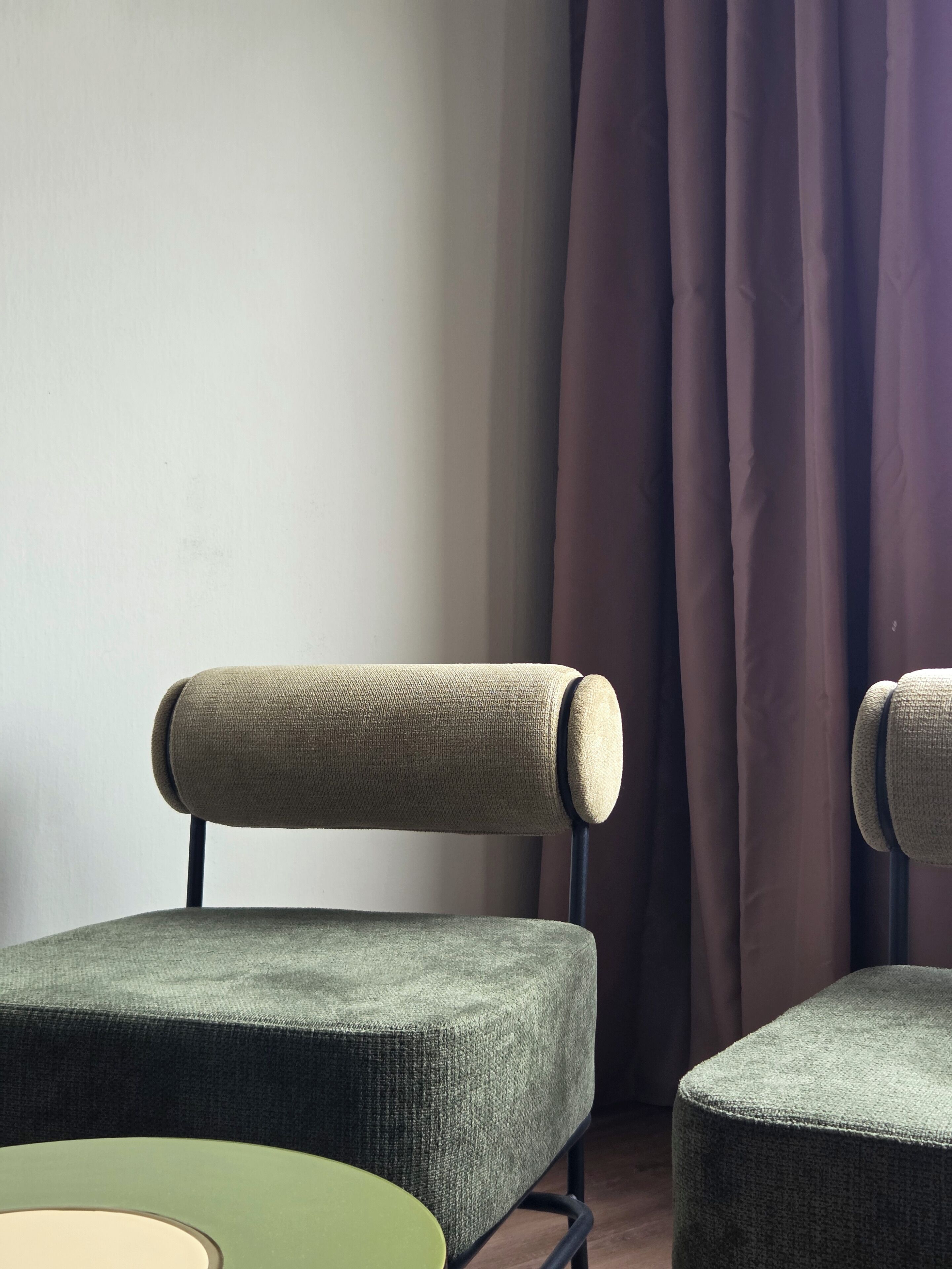 A chair with a cushioned backrest and armrests, a matching ottoman, and a round table with a green top.