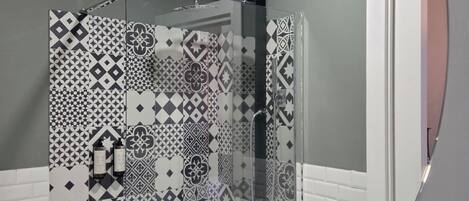 Casa de banho com zona de duche e design de azulejos padronizados.
