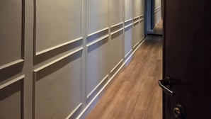 A hallway with a wooden floor and a door at the end. - Corso Italia Rooms (Milan)