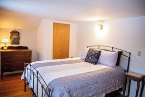A bedroom with a bed, wooden dresser, and a door. - Charming, Unique and Peaceful 3-bedroom Farmhouse on 500 acres in Great Bend, PA (Great Bend)