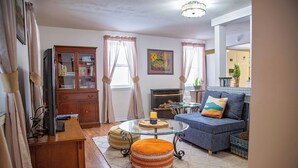 A living room with a glass coffee table, a blue sofa, and a wooden cabinet. - Charming, Unique and Peaceful 3-bedroom Farmhouse on 500 acres in Great Bend, PA (Great Bend)