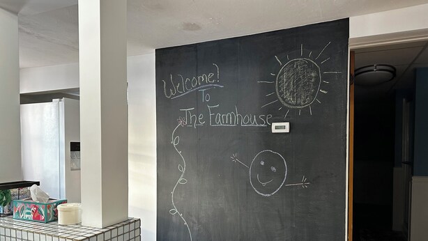 A room with a blackboard displaying a welcome message and drawings, a tiled bench, and a door leading to another room. - Charming, Unique and Peaceful 3-bedroom Farmhouse on 500 acres in Great Bend, PA (Great Bend)