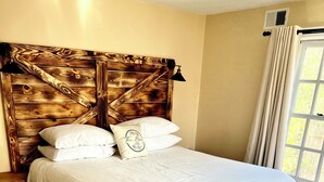 Un lit bien fait, avec du linge de lit blanc, une tête de lit en bois et une petite table de chevet.