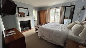 A bedroom with a bed, a fireplace, a television, and a wardrobe. - The Bond Inn Room #7 (Warrensburg)