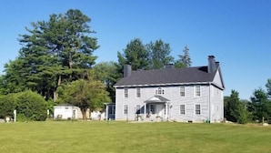 A large, two-story house with a symmetrical facade, a central entrance with a covered porch, and a well-maintained lawn in front. - The Bond Inn Room #7 (Warrensburg)