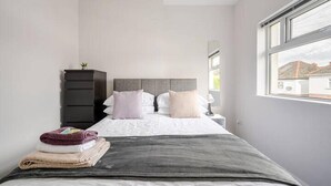Une chambre à coucher moderne avec un lit, une commode et une fenêtre.