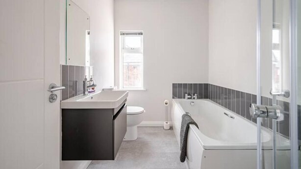 A modern bathroom with a large bathtub, a separate toilet, and a vanity with a mirror.