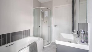 Une salle de bain moderne dotée d’une douche à parois de verre, d’une baignoire et d’un meuble-lavabo avec un miroir.