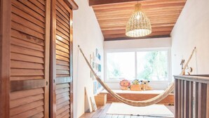 Un interior de madera con una hamaca, pisos de madera y una lámpara en el techo.