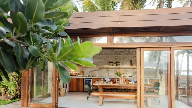 Una cocina moderna con un banco de madera, una mesa de comedor y vistas al exterior.