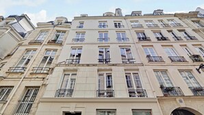 Un immeuble à plusieurs étages, de style architectural classique, caractérisé par des fenêtres et des balcons disposés de manière symétrique.