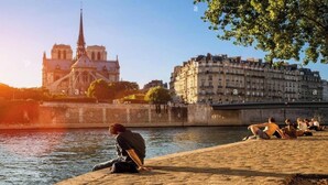 Une vue sur le fleuve, avec une cathédrale historique et des bâtiments modernes en arrière-plan.